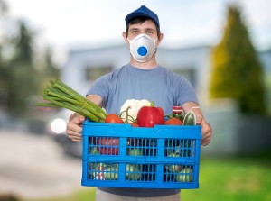 Man with FFP3 respirator face mask is delivering food and groceries during virus epidemic.